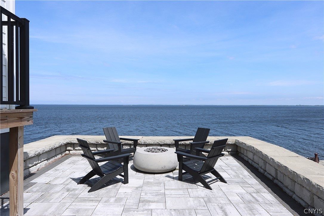 Stone terrace with fire pit and Adirondack chairs overlooking Lake Ontario
